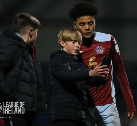 4 March 2022; Issa Kargbo of Cobh Ramblers takes a 'selfie' with a supporter after the SSE Airtricity League First Division match between Cobh Ramblers and Treaty United at St Colman's Park in Cobh, Cork. Photo by Michael P Ryan/Sportsfile